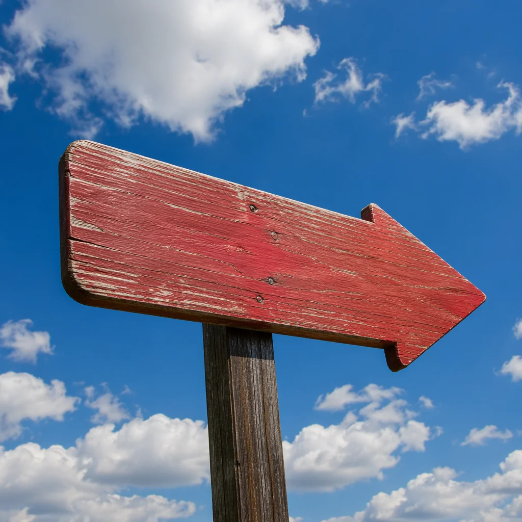 Red Wooden Arrow Sign Under Blue Sky