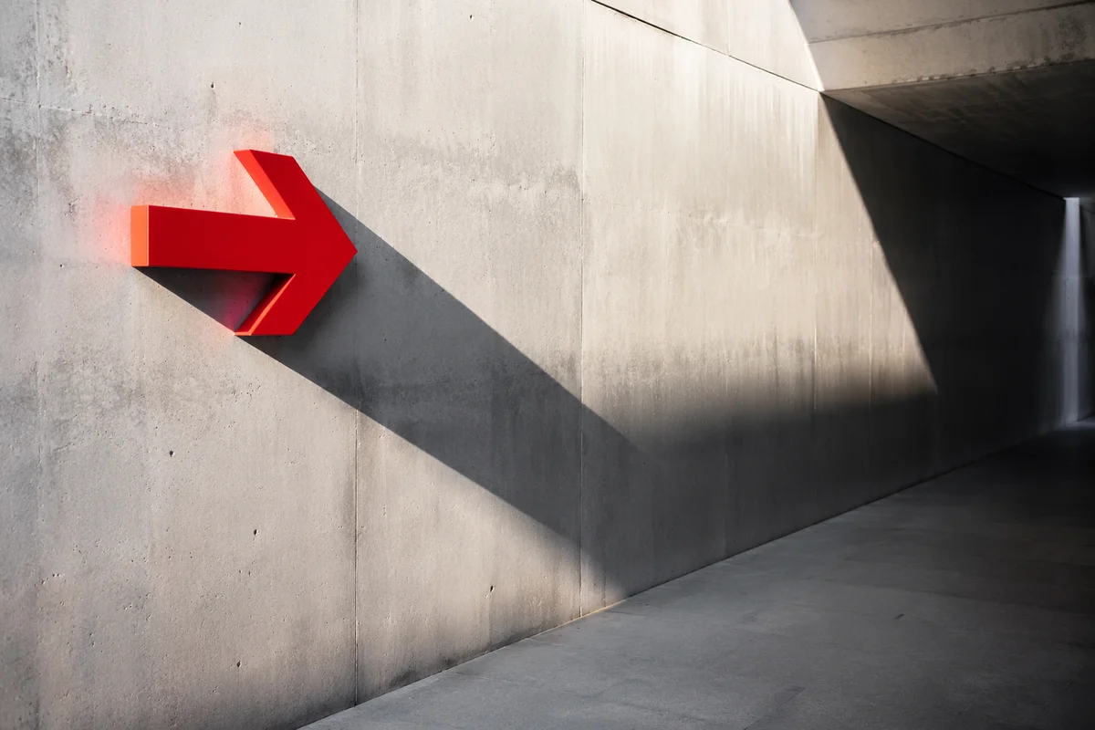Red Arrow Sign on Concrete Wall