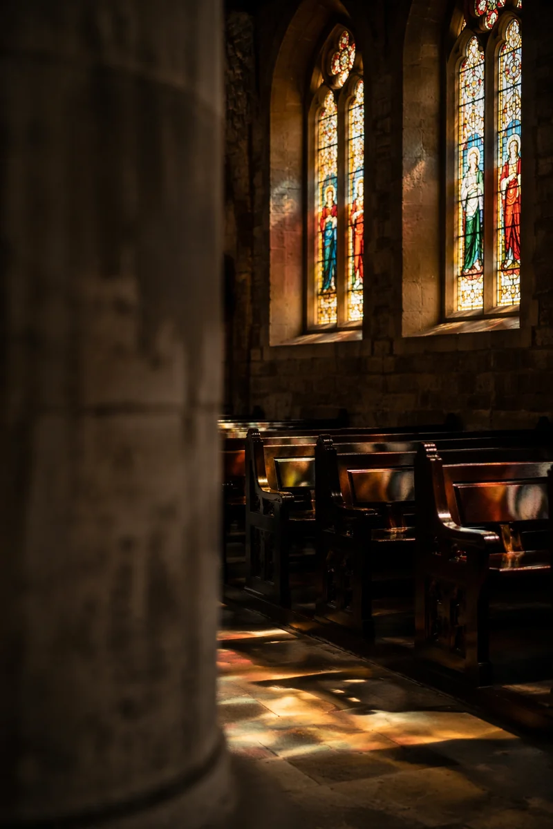 Sunlit Church Pews Beneath Stained Glass