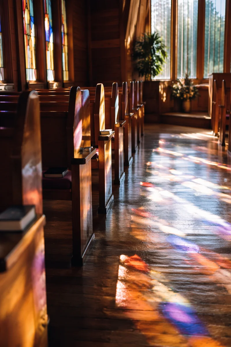 Sunlit Chapel Pews With Stained Glass