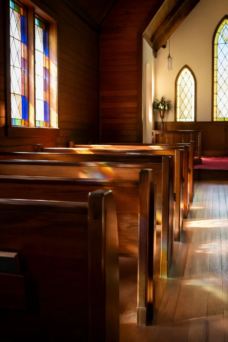 Sunlit Wooden Chapel Pews With Stained Glass