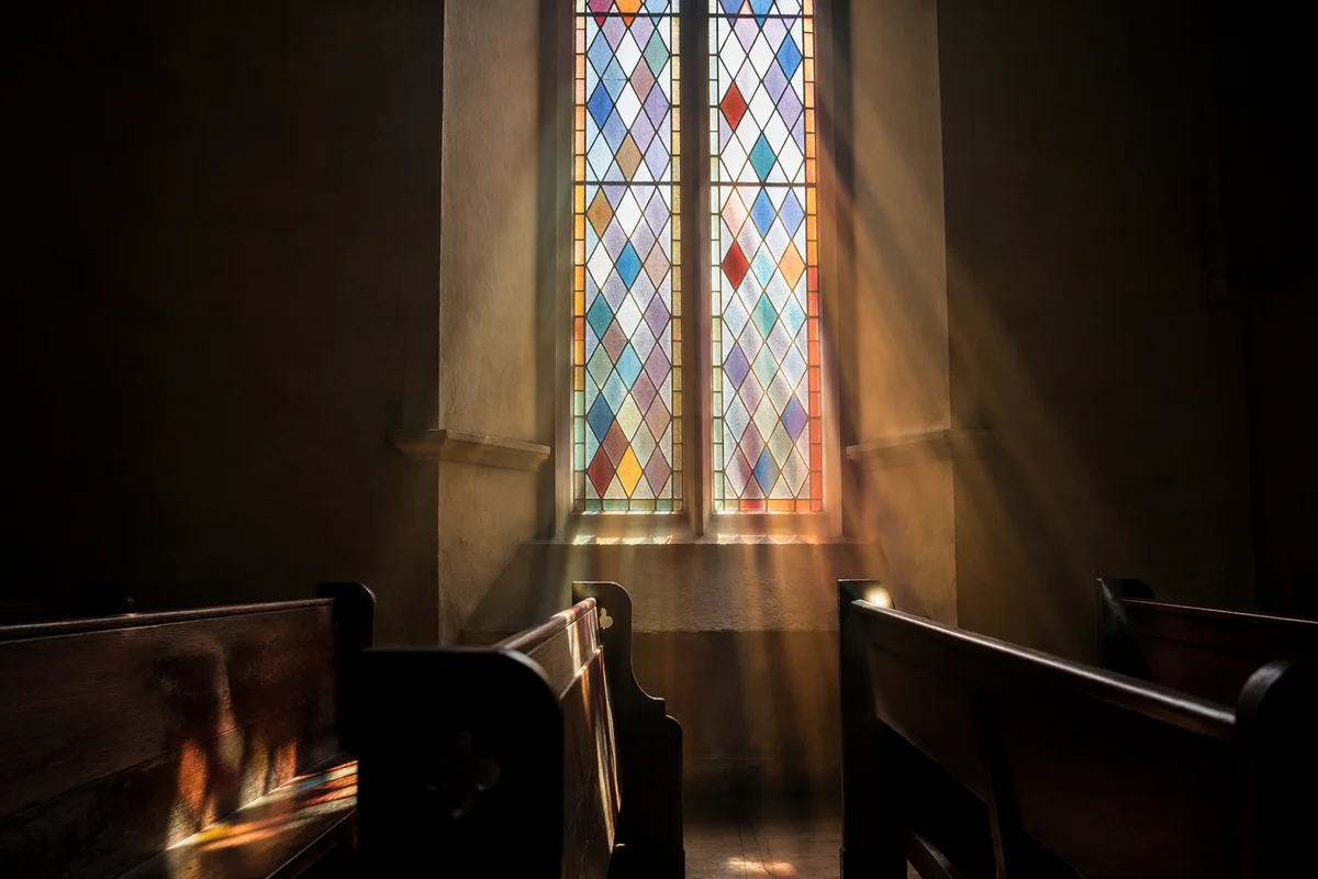 Sunlit Chapel Pews and Stained Glass