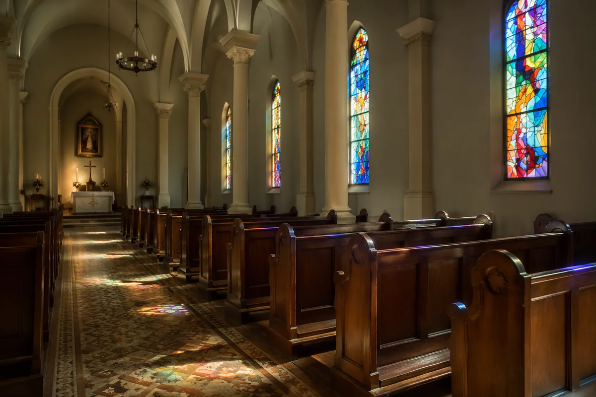 Sunlit Chapel Pews with Stained Glass