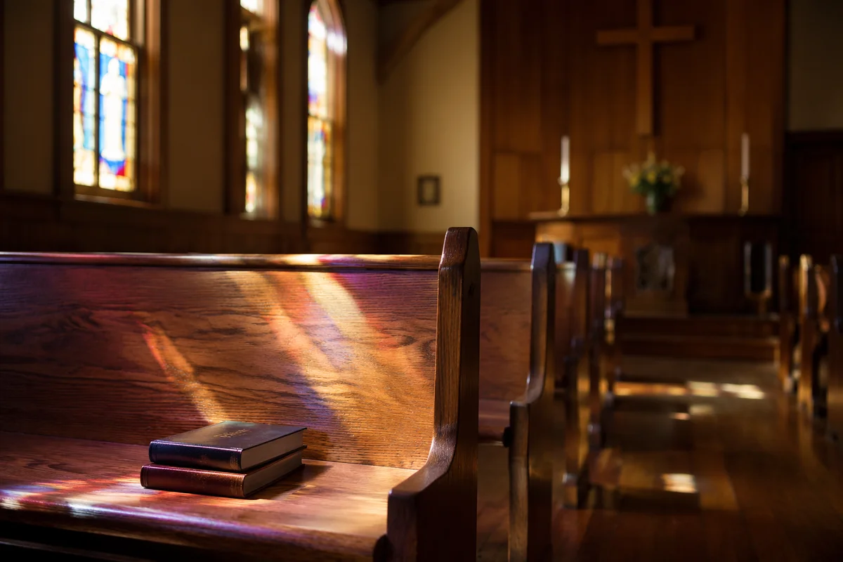 Sunlit Chapel Pews with Stained Glass