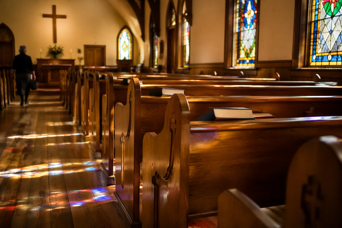 Sunlit Chapel Pews With Stained Glass