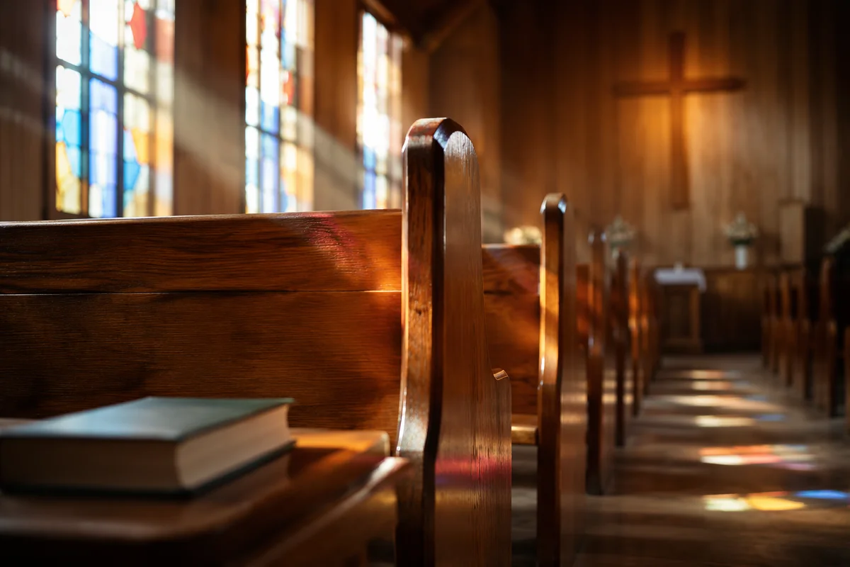 Sunlit Chapel Pews with Stained Glass
