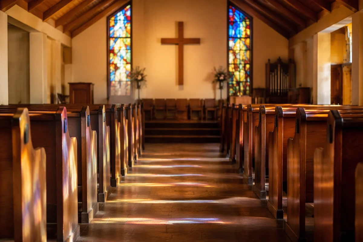 Sunlit Chapel Pews with Stained Glass