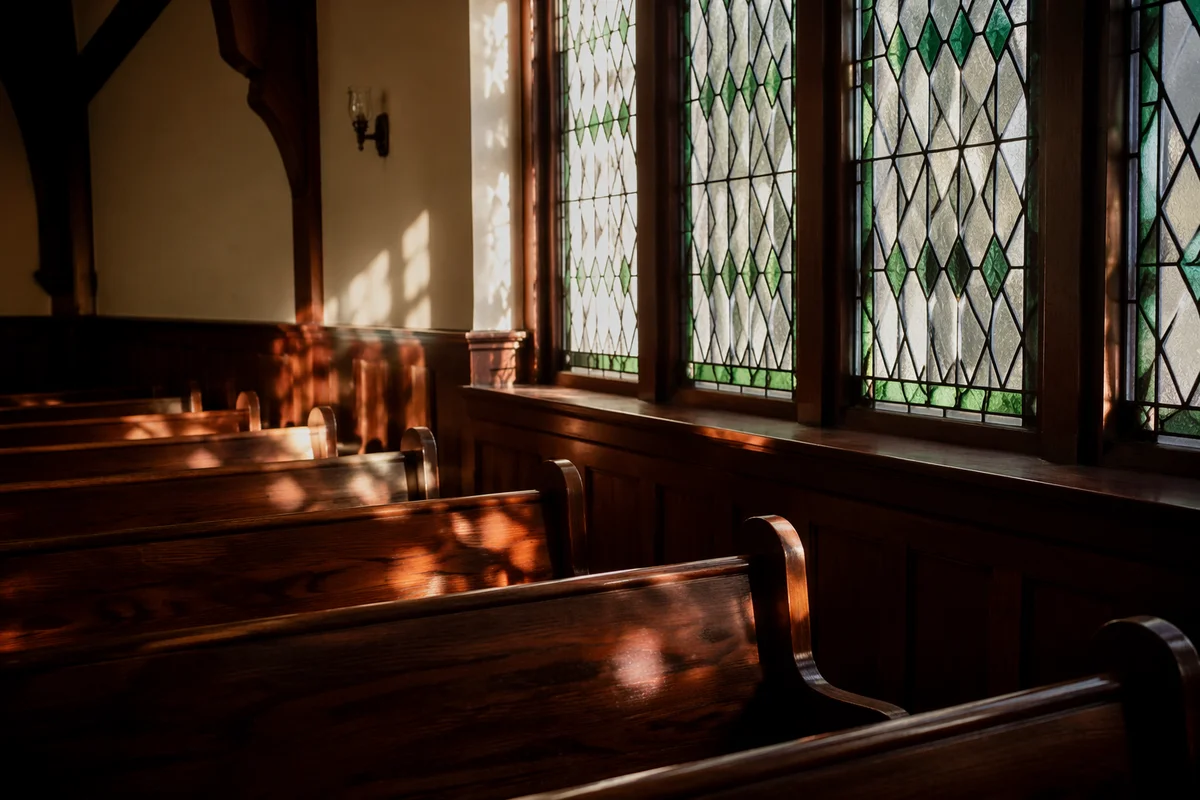 Sunlit Chapel Pews with Stained Glass