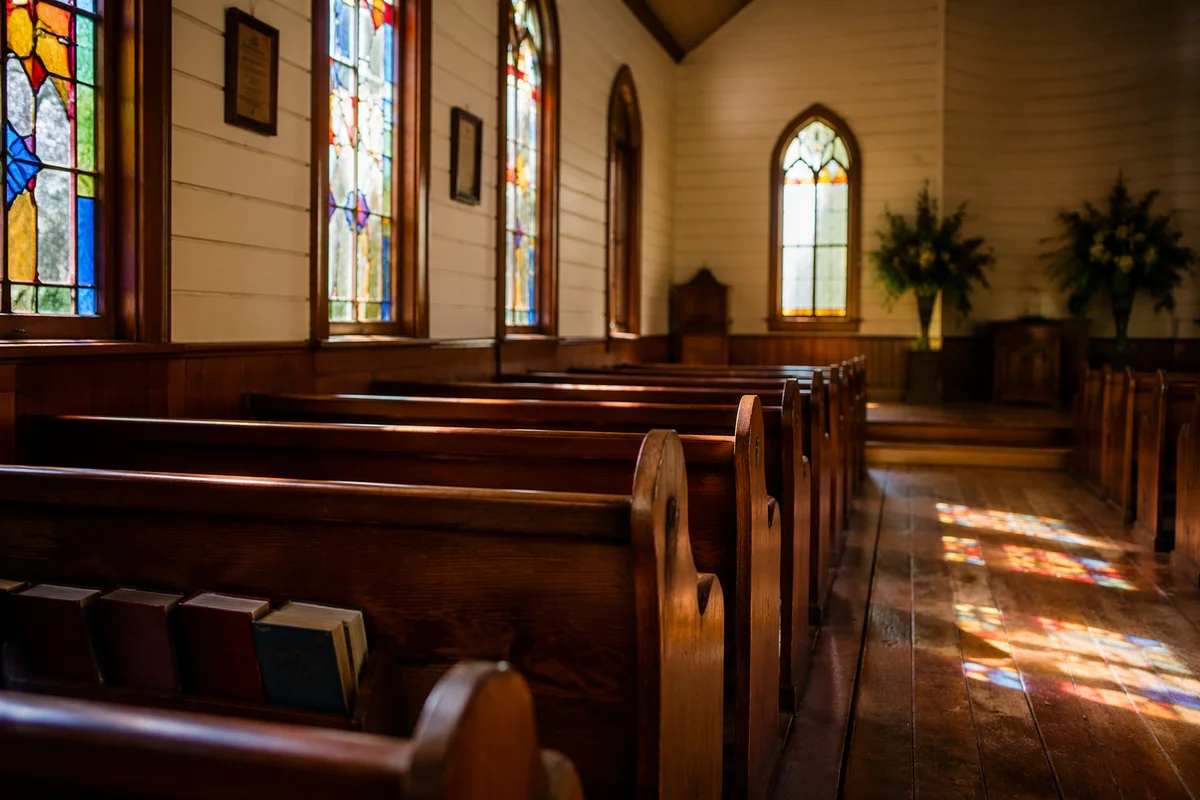Sunlit Wooden Chapel Pews with Stained Glass