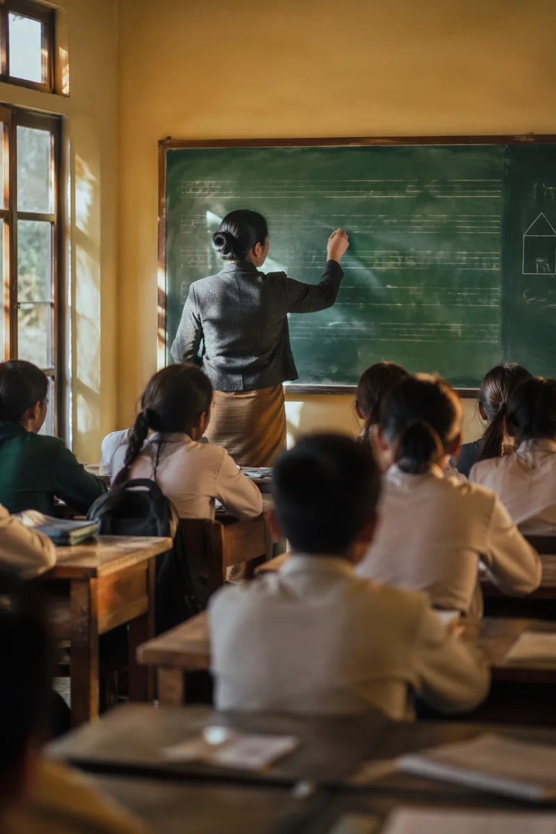 Teacher Writing on Green Chalkboard