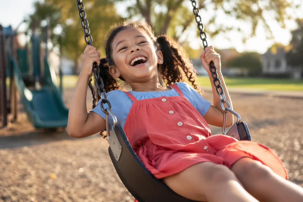 Laughing Little Girl on Playground Swing