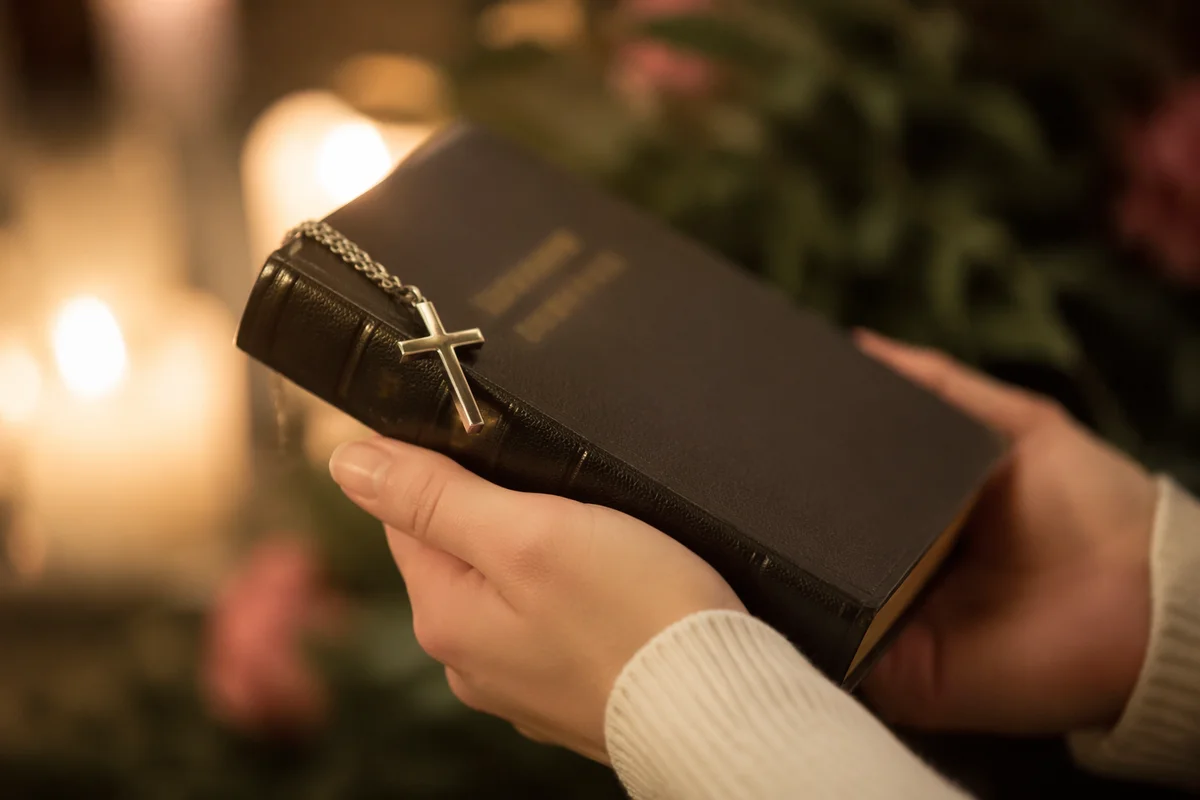 Hands Holding Bible with Cross Pendant