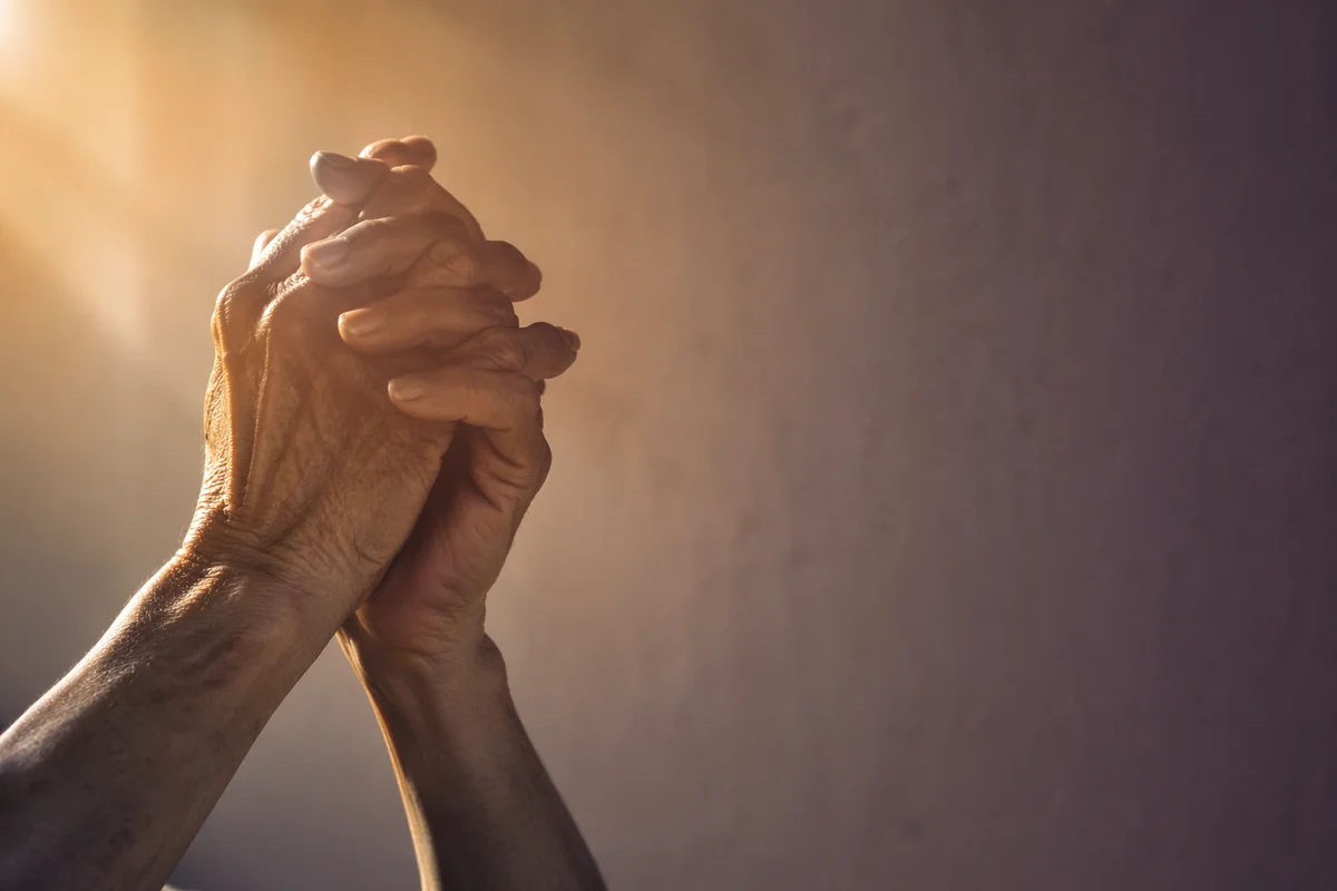 Older Hands Praying in Warm Soft Light