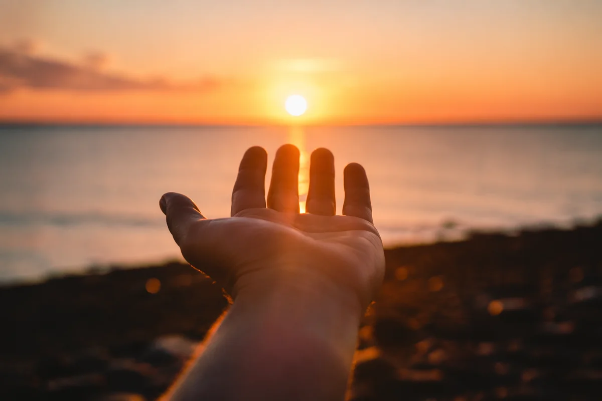 Hand Reaching Toward Sunset Light