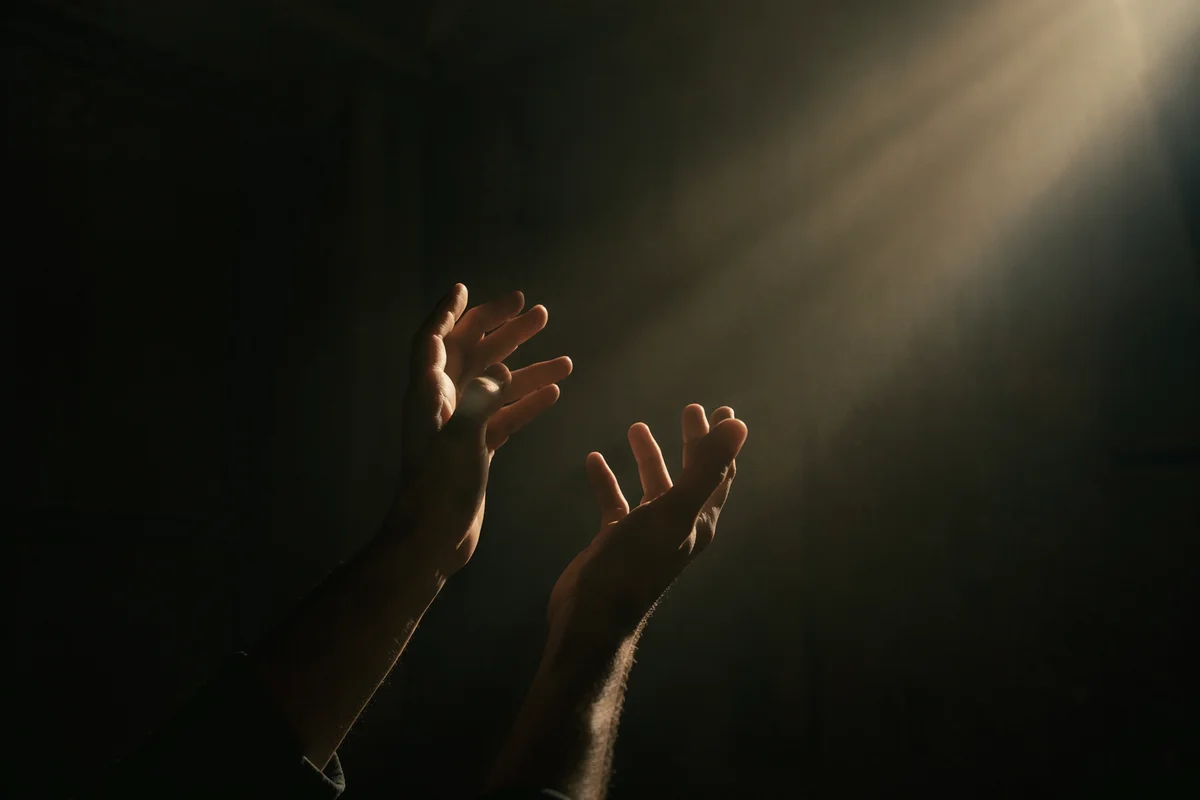 Hands Reaching Toward Warm Light