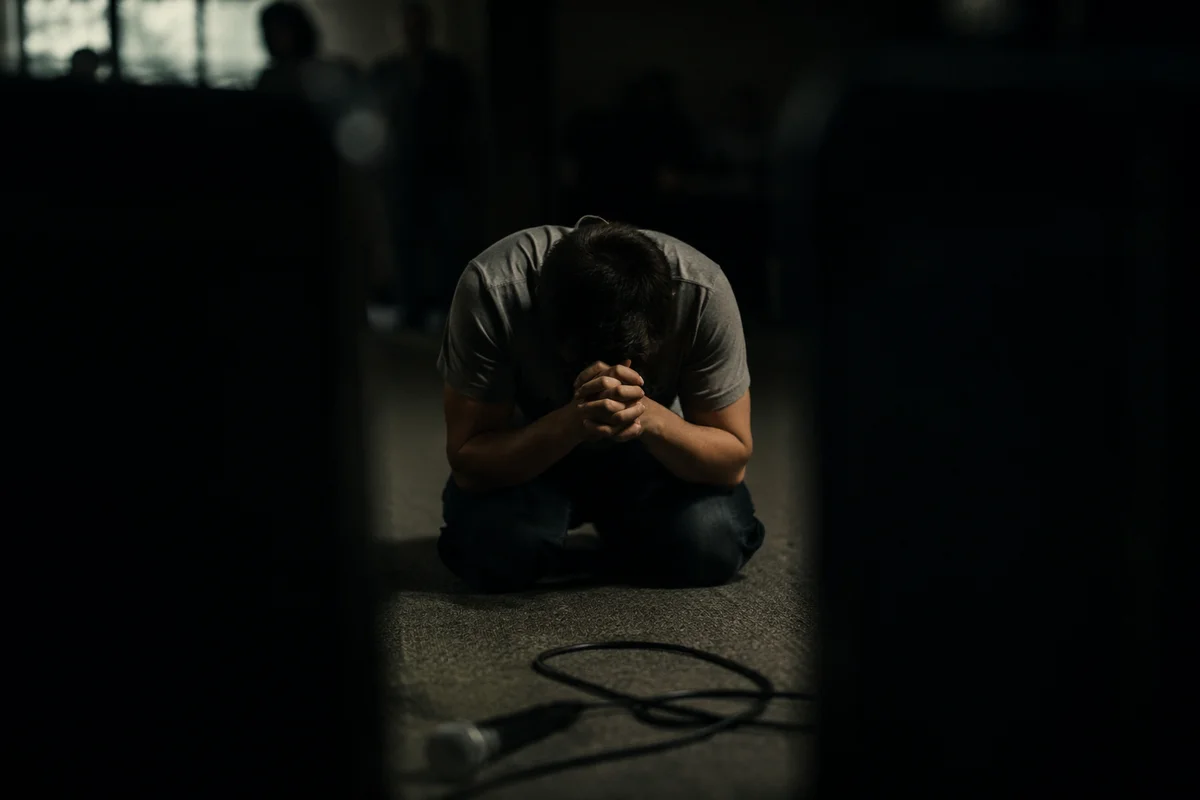 Person Kneeling in Dim Prayer Room