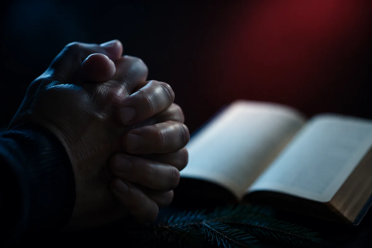 Praying Hands Beside Open Bible