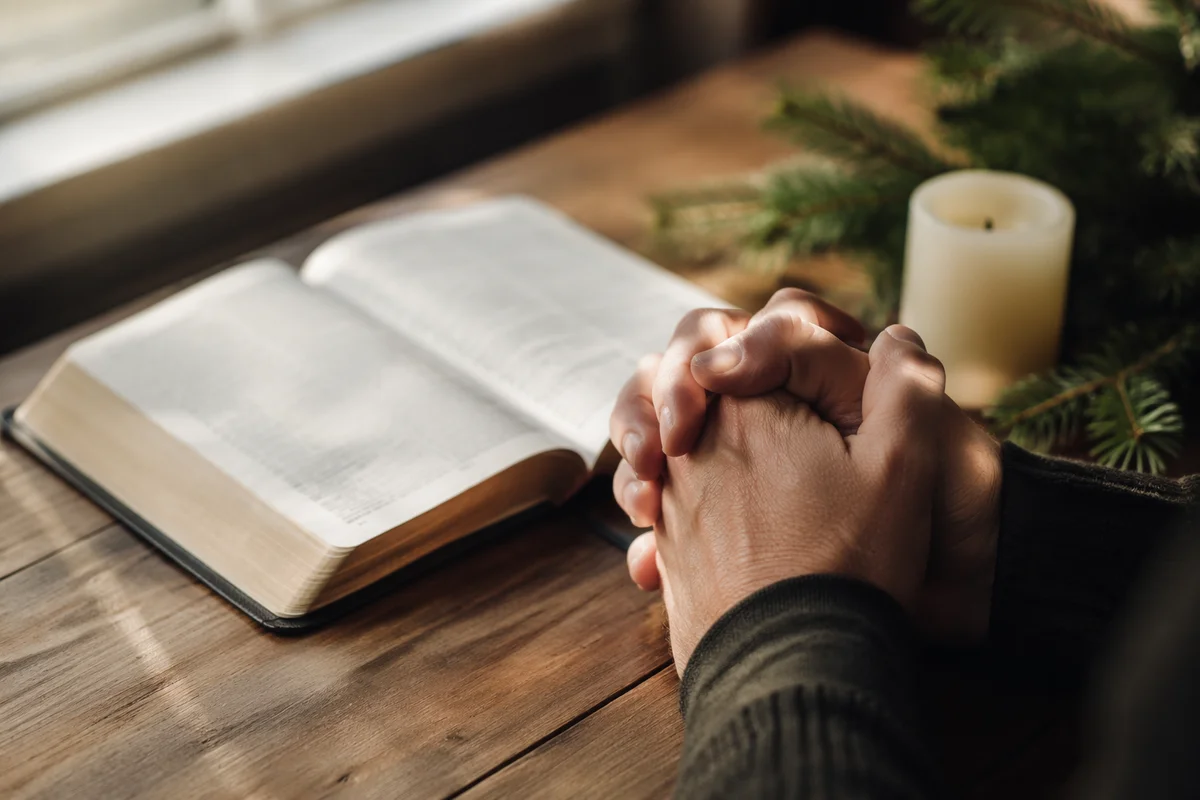 Praying Hands Beside Open Bible
