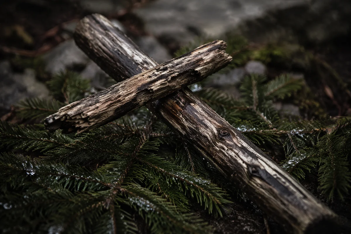 Weathered Wooden Cross Among Evergreen Branches