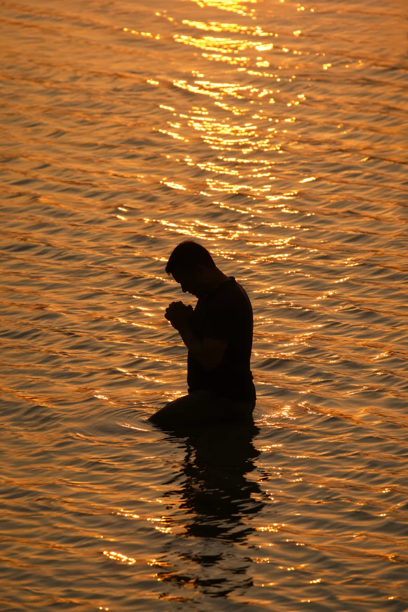 Silhouetted Prayer in Golden Sunset Waters