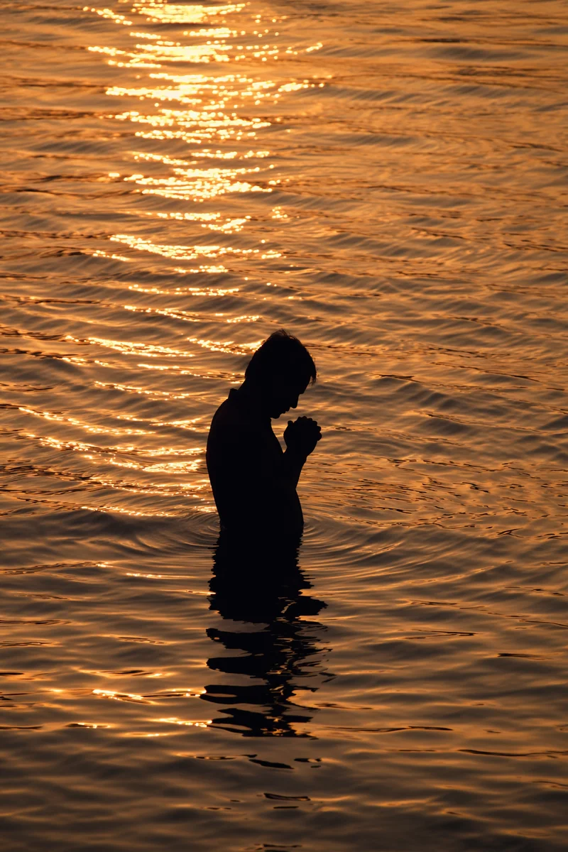 Silhouette Praying in Golden Sunset Waters