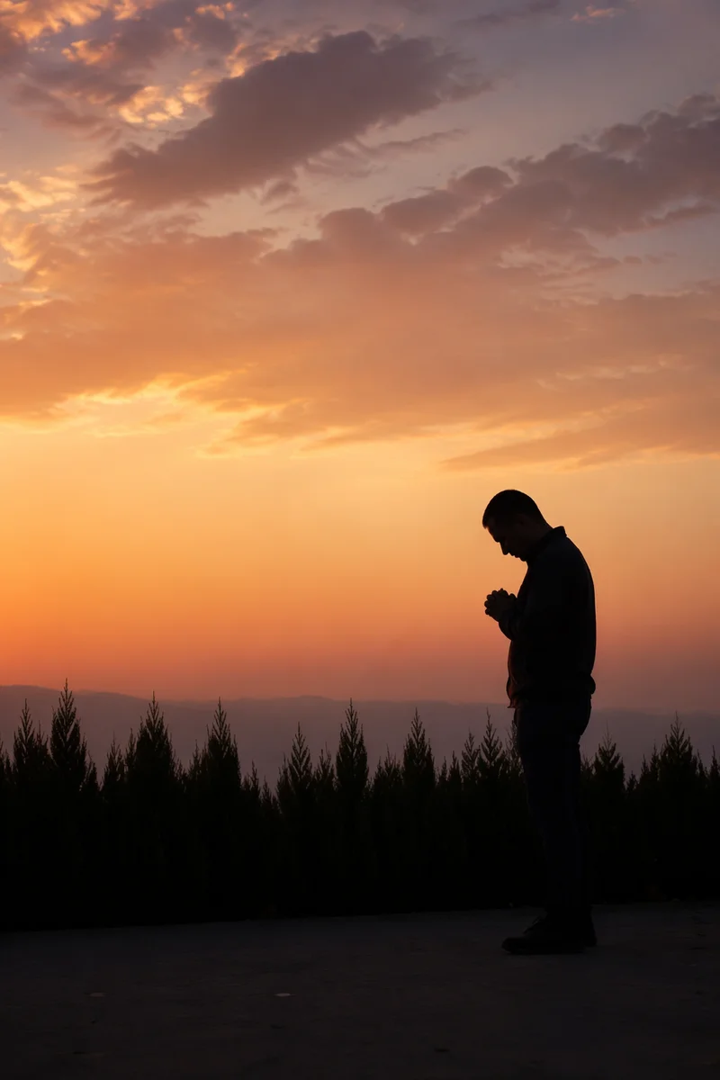 Silhouetted Prayer Beside Evergreens at Sunset