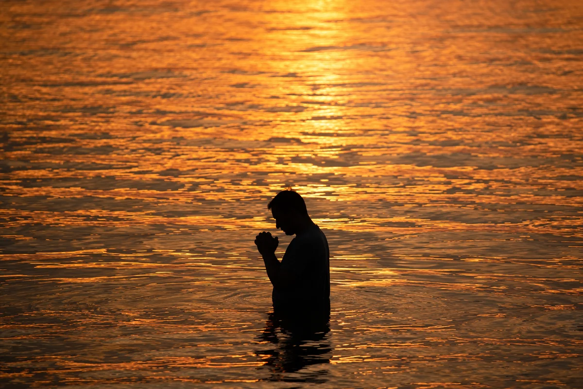 Silhouetted Prayer in Golden Sunset Water
