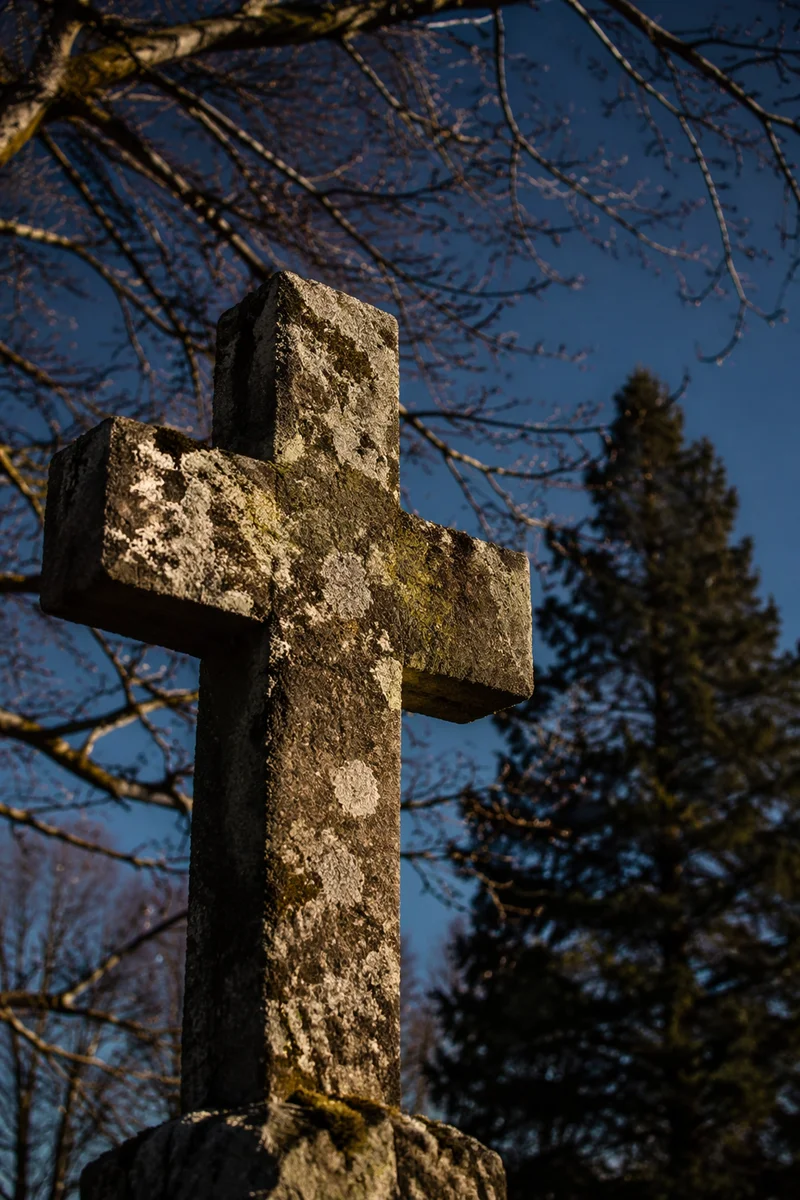 Weathered Stone Cross Beneath Evergreen Sky