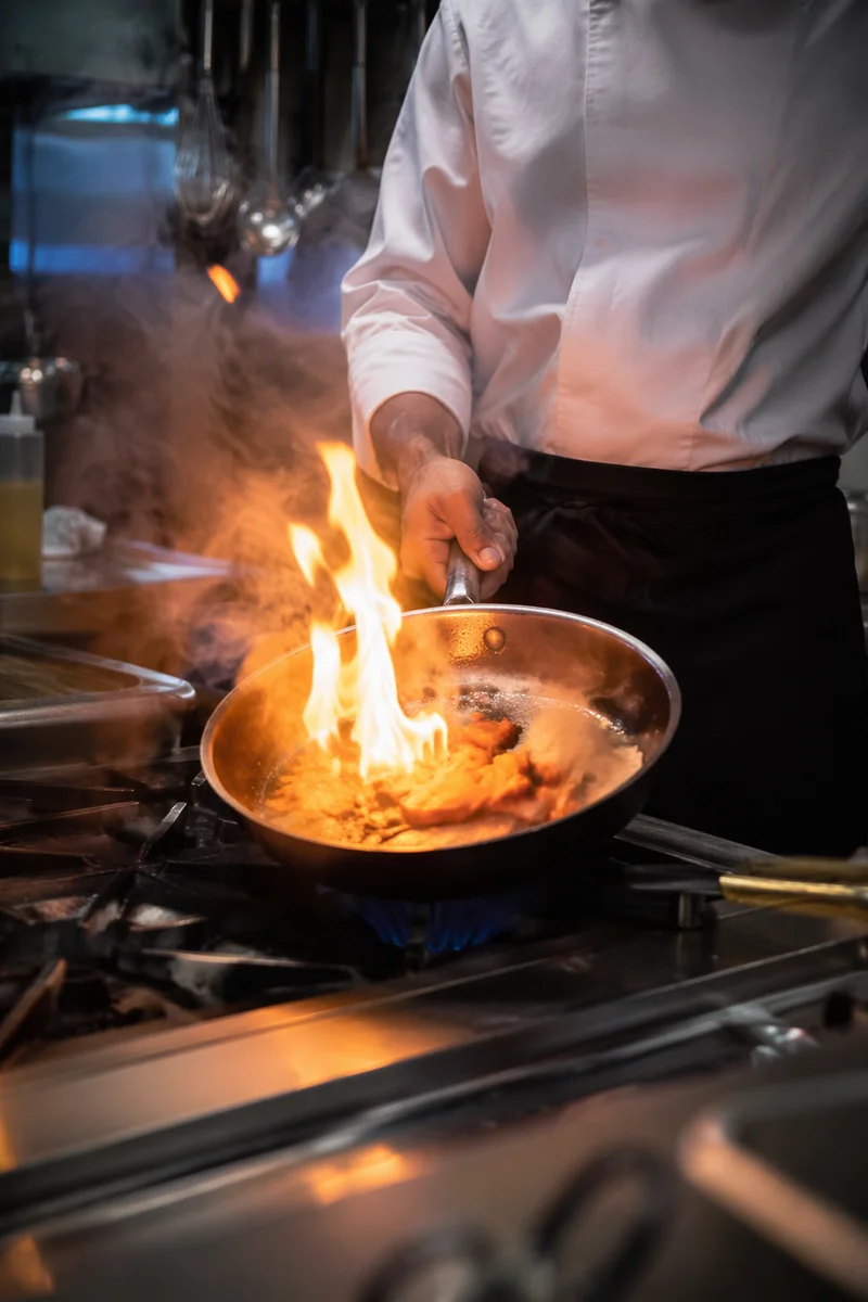 Chef Tossing Vegetables Over Kitchen Flame