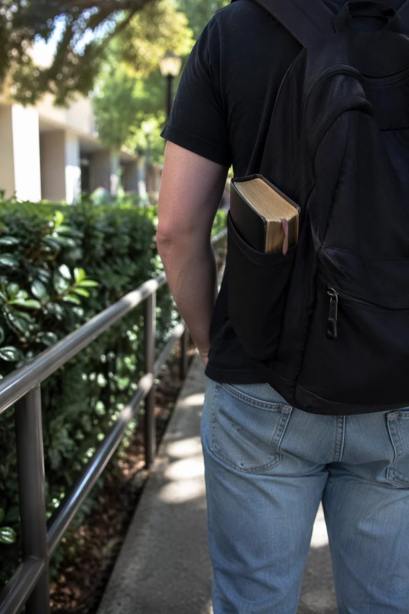 Bible in Backpack on Campus Walkway