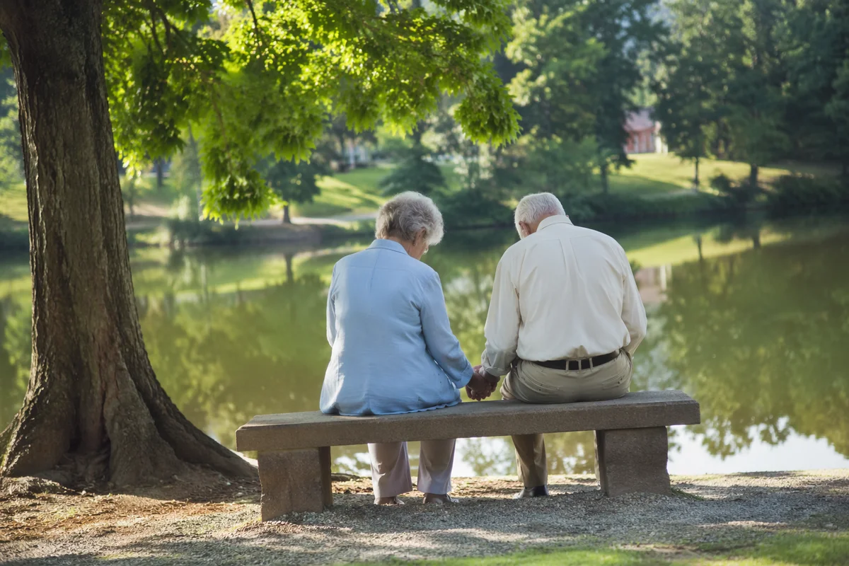 Elderly Couple Praying on Peaceful Park Bench