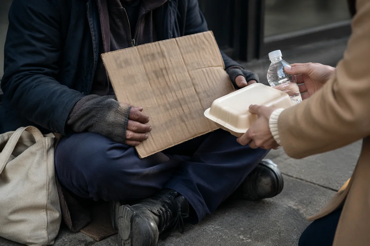 Volunteer Offering Meal to Homeless Person