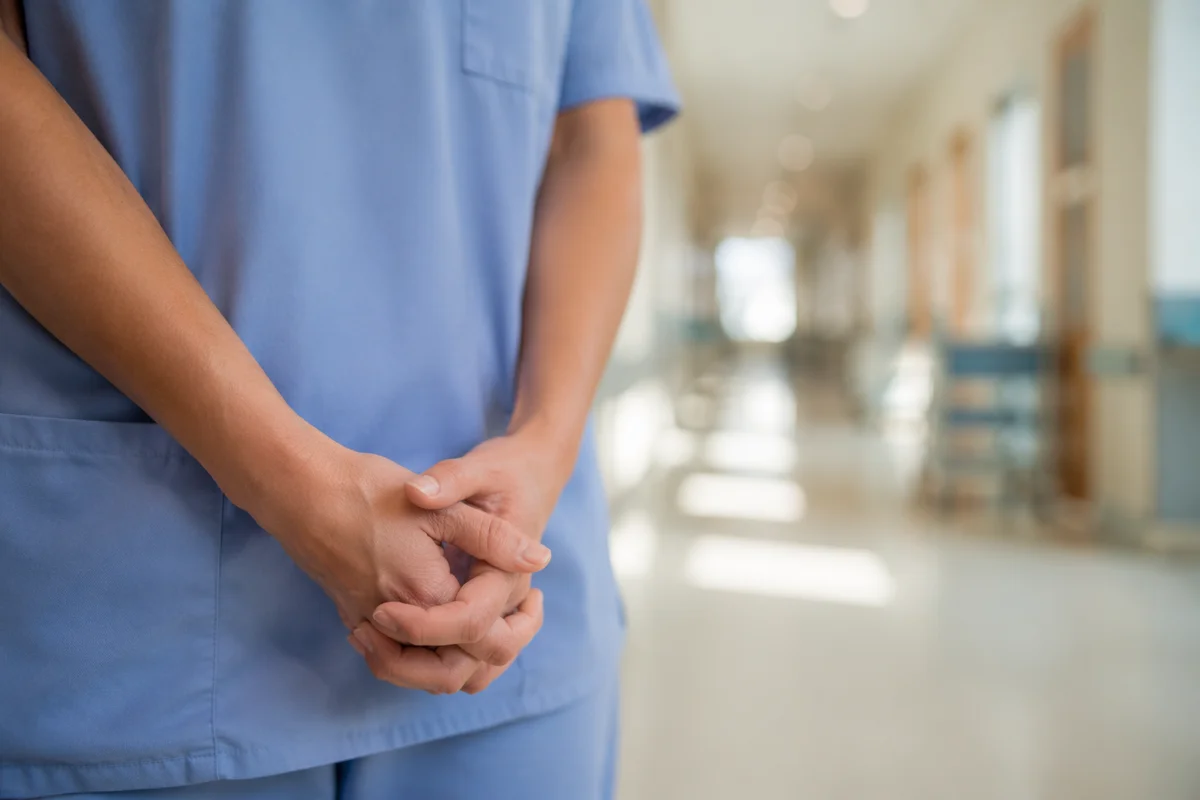 Nurse Hands Praying in Hospital Corridor