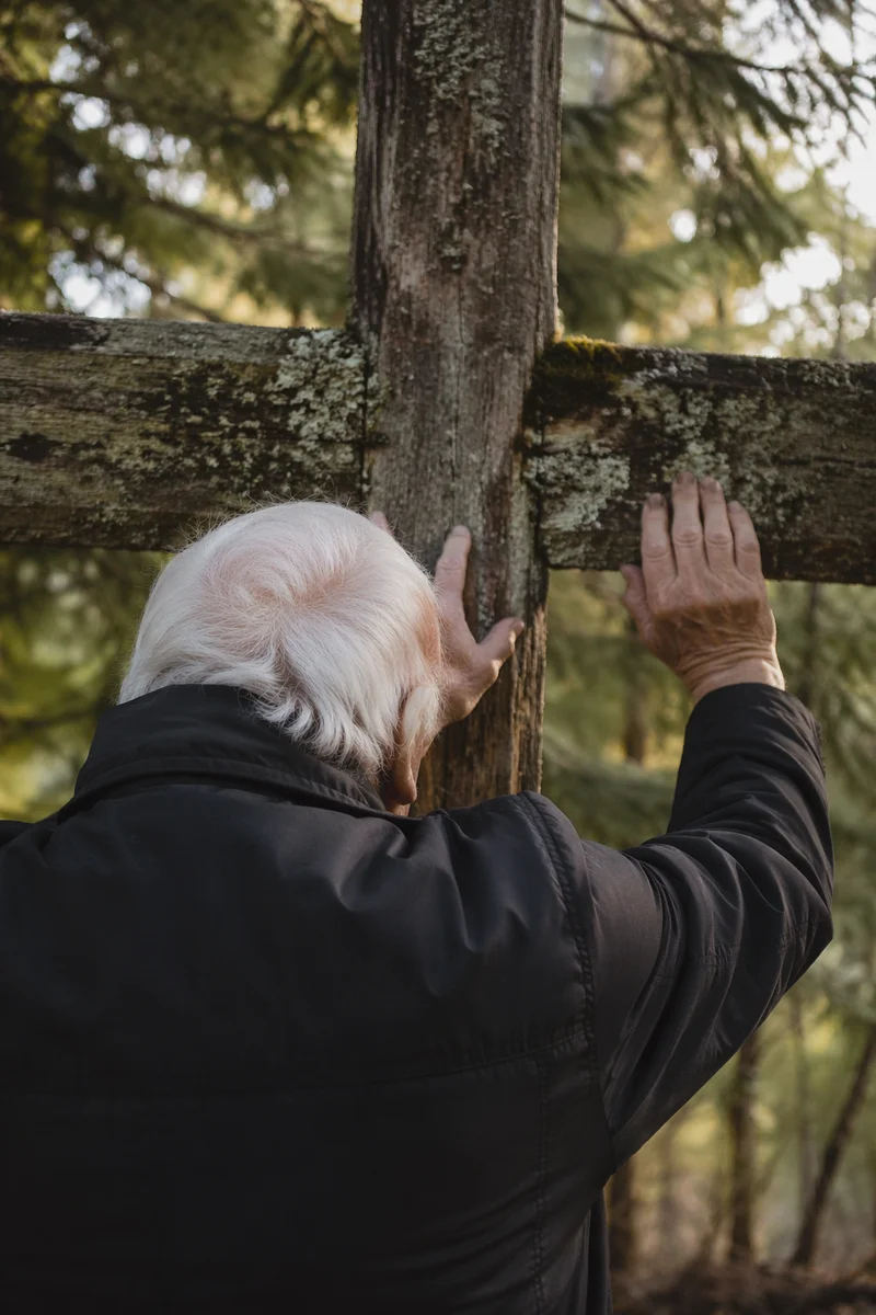 Older Believer Carrying Cross Uphill
