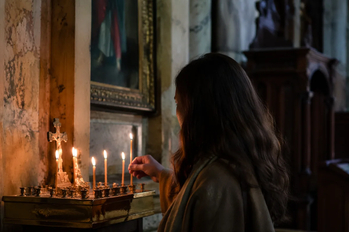 Person Lighting Candle in Dim Church