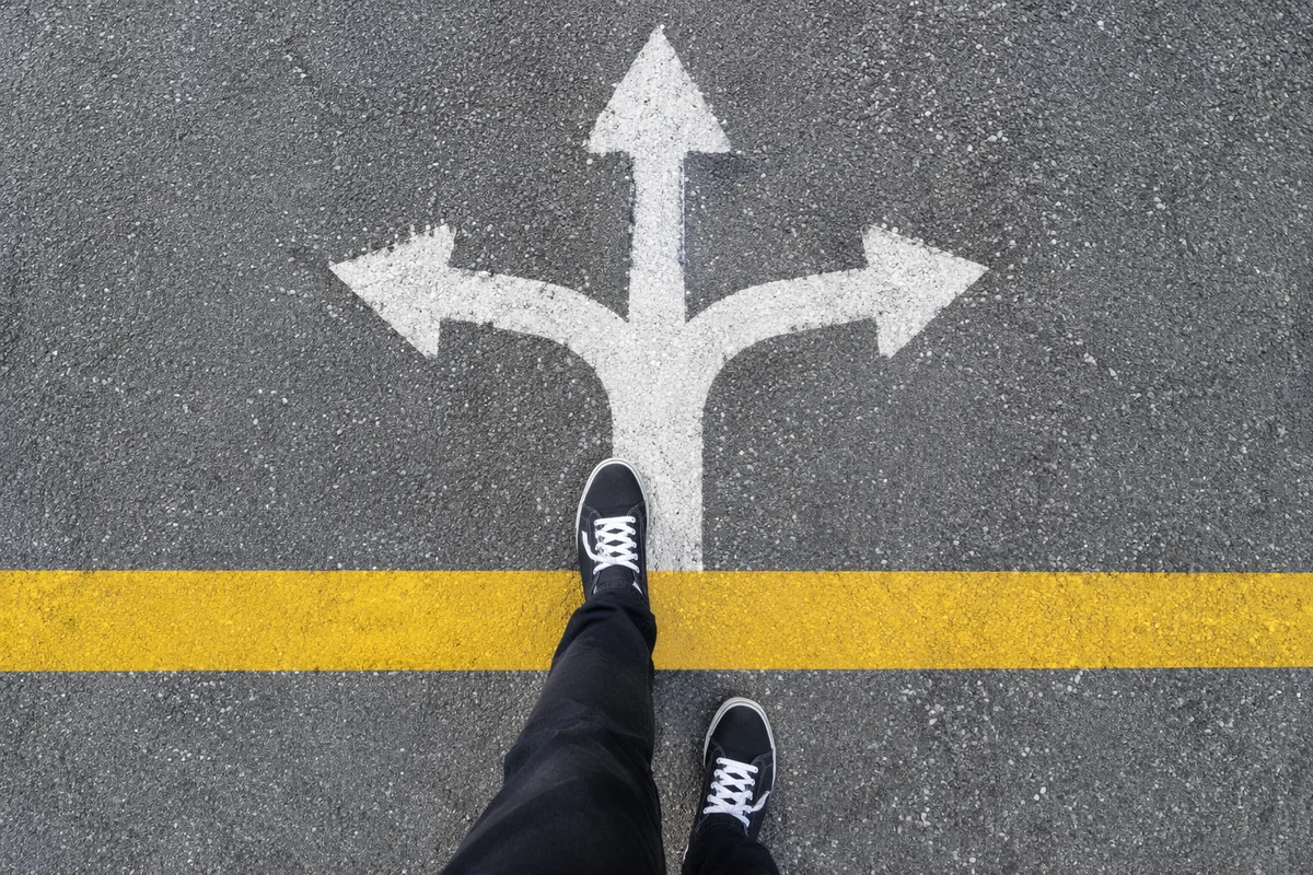 Person Choosing Direction at Road Crossroads