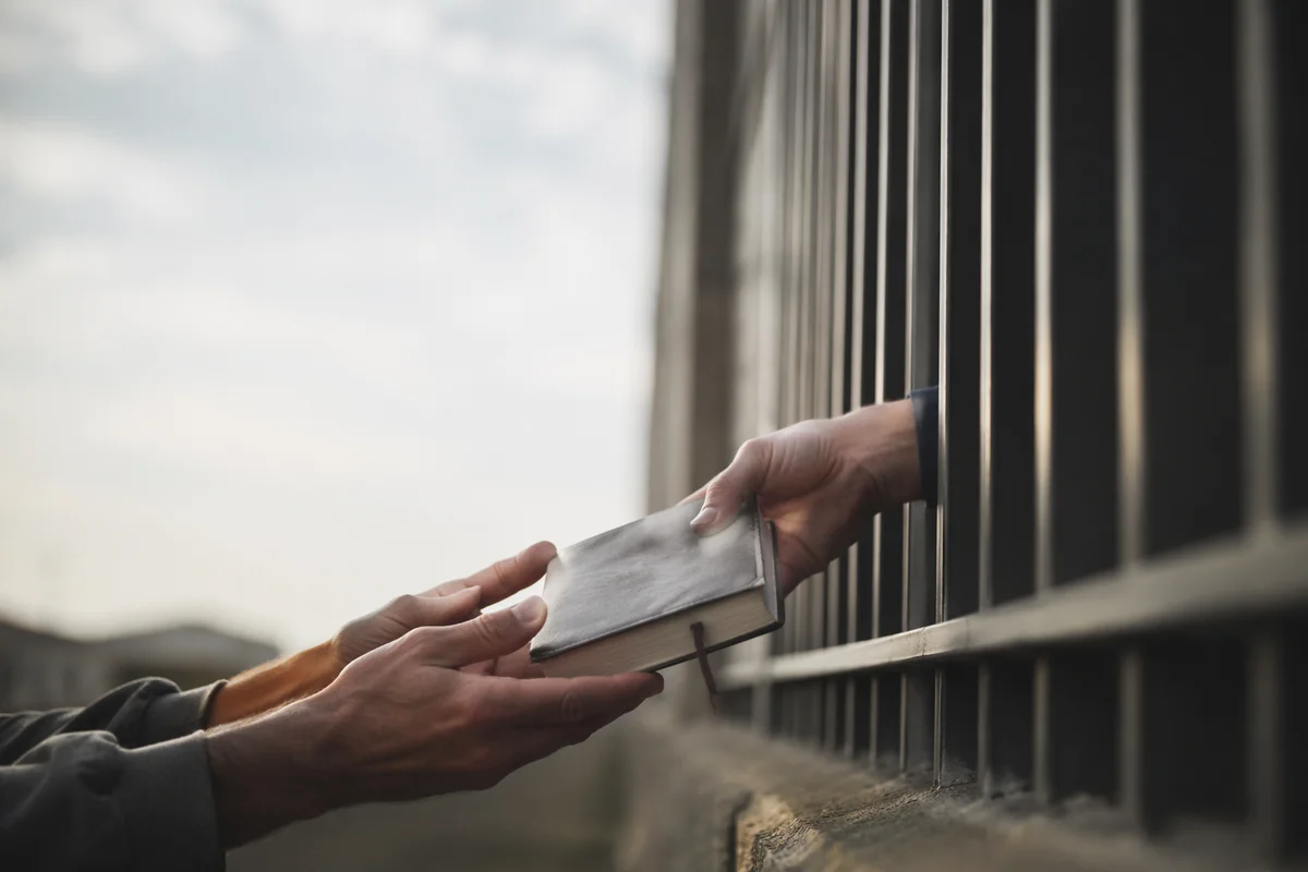 Hands Reaching Through Prison Bars