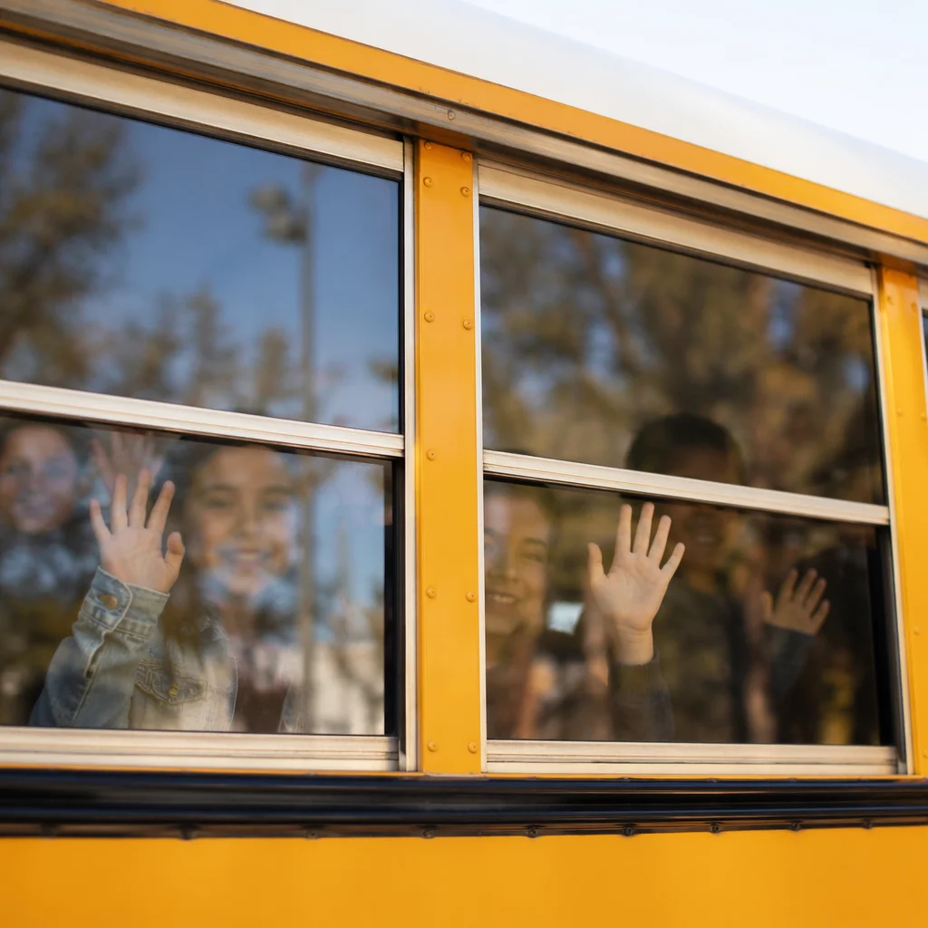 Children Waving From School Bus Window