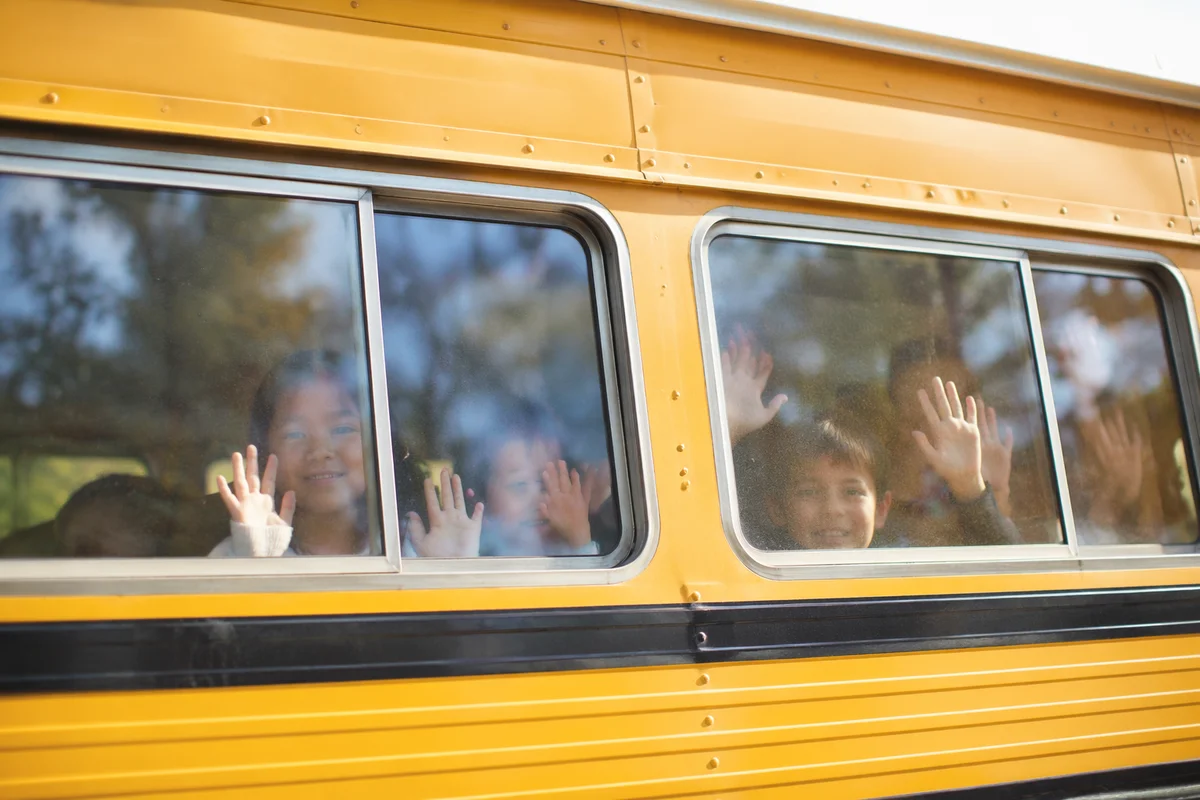 Children Waving From School Bus Window