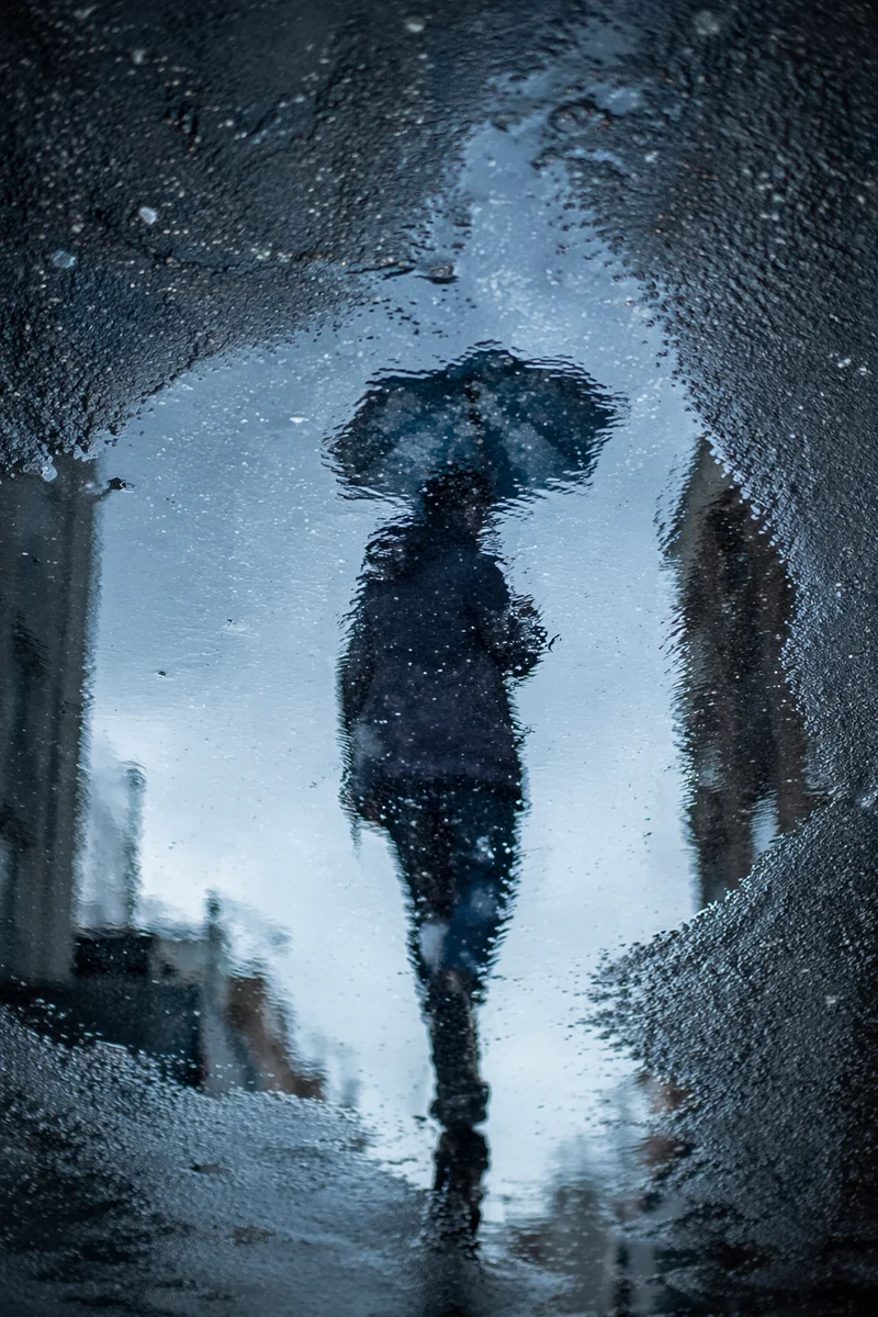 Umbrella Reflection in Rainy City Puddle