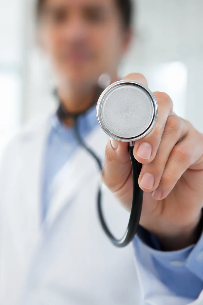 Clinician Holding Stethoscope in Exam Room