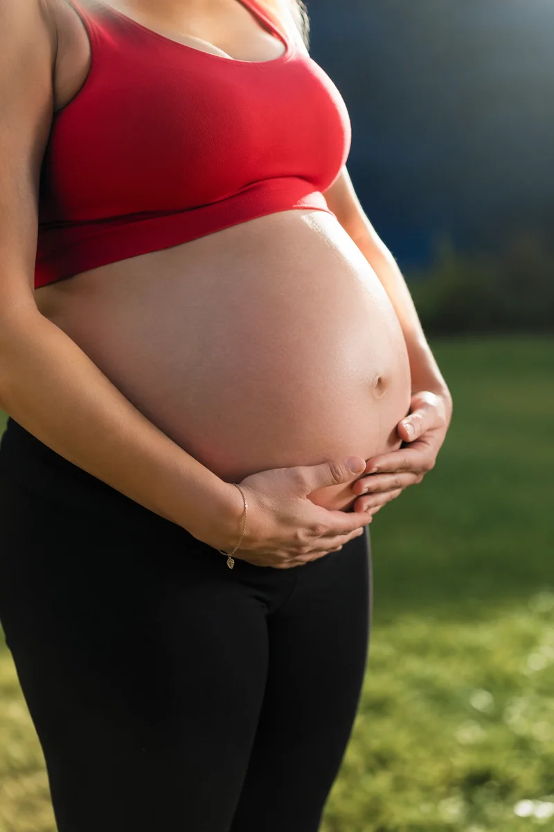 Pregnant Woman Cradling Belly Outdoors