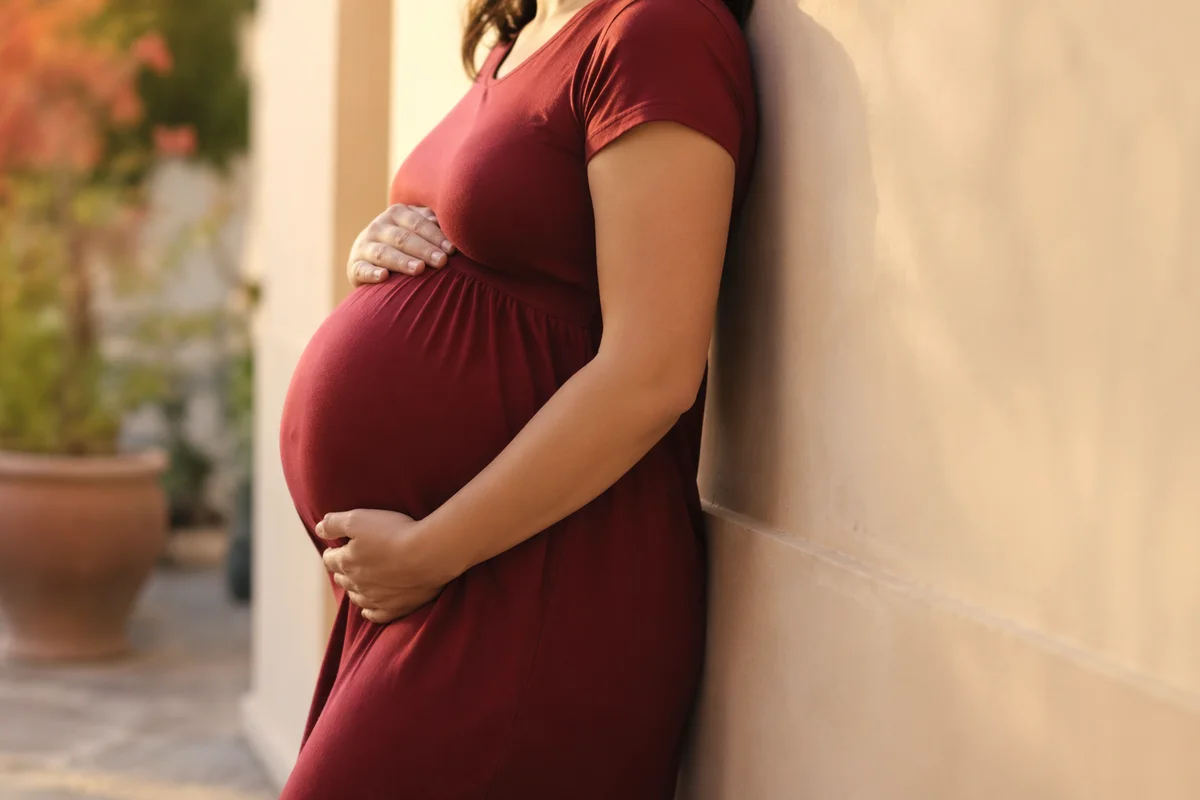 Pregnant Woman Cradling Belly Outdoors
