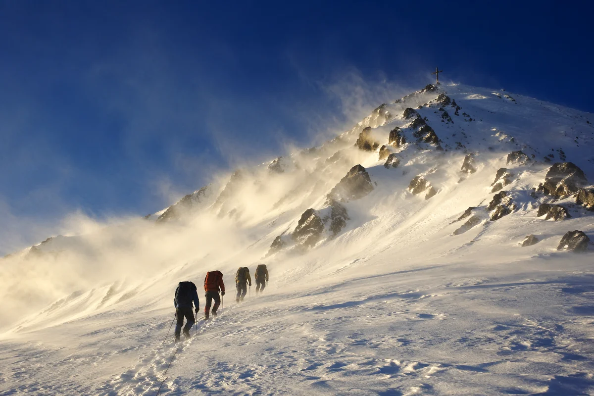 Climbers Approaching Summit Cross at Sunrise