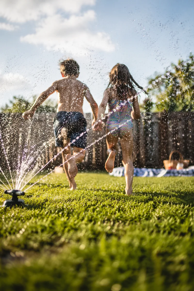 Children Running Through Summer Sprinkler Joy