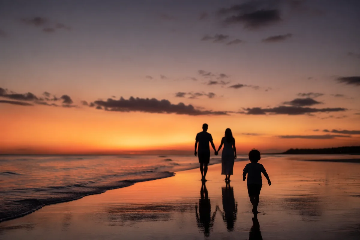 Family Silhouettes Walking on Beach at Sunset