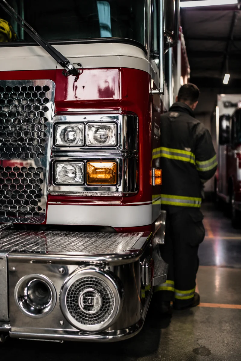 Firefighter Beside Red Fire Truck Station