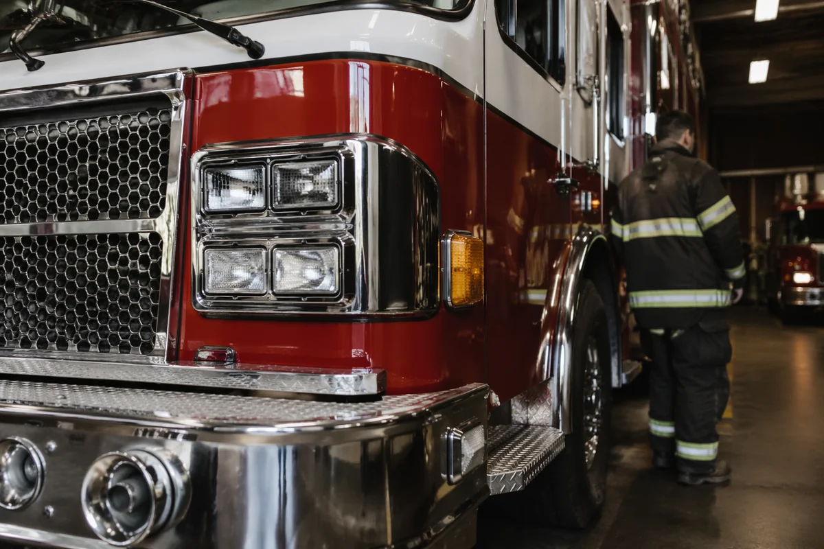 Firefighter Beside Fire Truck in Station
