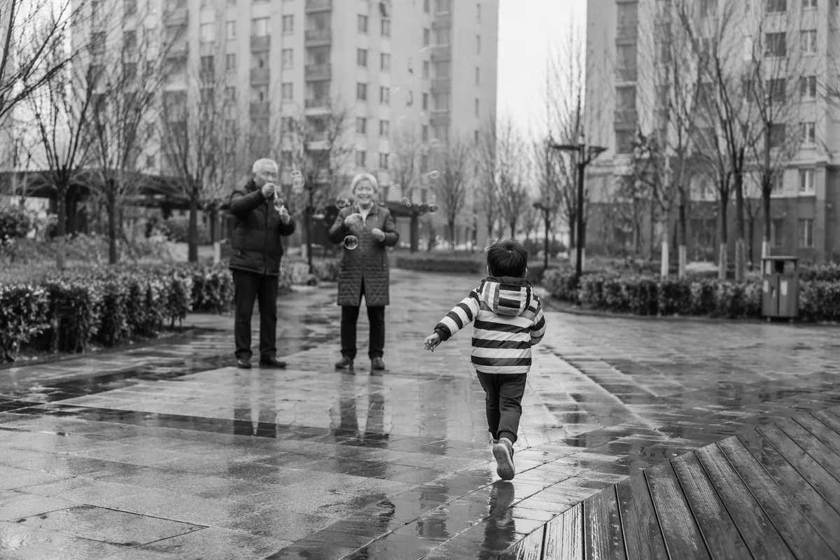Grandparents and Grandchild in Rainy Courtyard