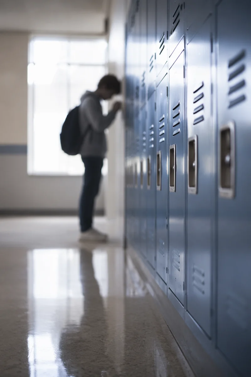 High School Student Praying by Lockers